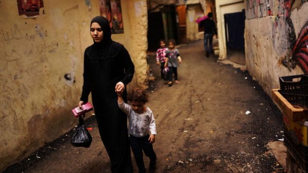 A Syrian woman displaced by the war walks with her child in a neighborhood with a high concentration of Syrian refugees on November 9, 2013 in Beirut, Lebanon.  [Spencer Platt/Getty Images]