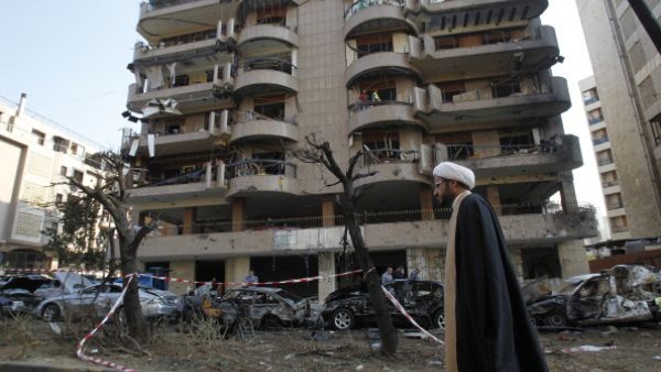 A Shiite cleric walks past a damaged building on November 20, 2013 at the scene of the previous day's double suicide bombing outside the Iranian embassy in Beirut. [AFP]