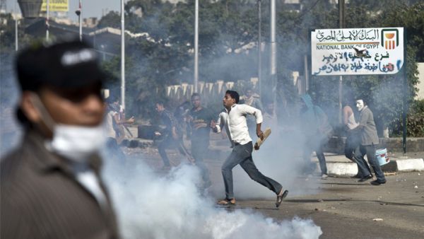 Egyptian students of al-Azhar university run for cover from a tear gas canister fired by riot police during clashes outside their university. [ AFP photo / Khaled Desouki]