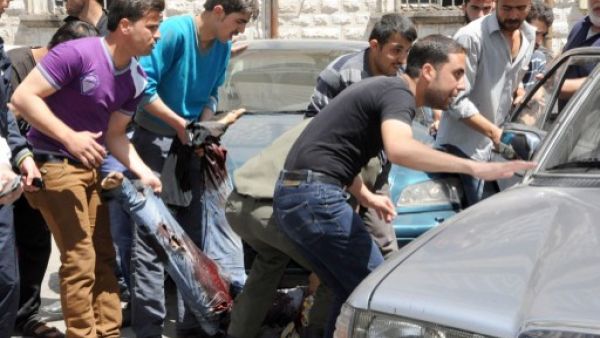 مواطنون سوريون يحاولون اسعاف جريح في التفجير الذي وقع ، الثلاثاء، في المرجة وسط دمشق/أ.ف.ب