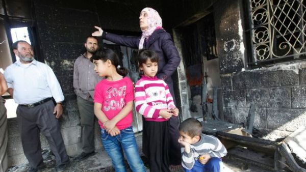 Palestinian family shows damage to their home after unknown assailant set it on fire, Thursday, November 14, 2013. [Haaretz.com]