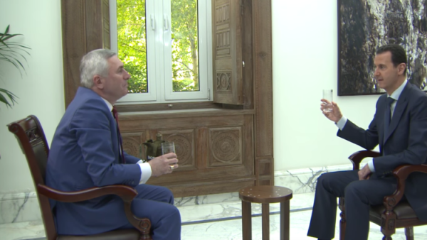 صحفي بيلاروسي يقدم كأسا من الماء للرئيس السوري بشار الأسد 