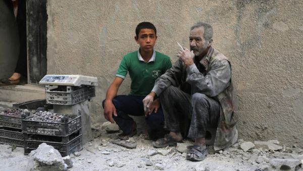 A man covered with dust sits on a street following a reported airstrike by Syrian government forces in the rebel-held neighborhood of Sukkari in Aleppo on May 30, 2016. (AFP/Baraa al-Halabi)