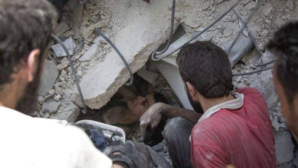 Syrian civil defence volunteers, known as the White Helmets, dig out a young boy trapped under the rubble of destroyed buildings following reported air strikes on the rebel-held neighbourhood of Al-Mashhad in the northern city of Aleppo, on July 25, 2016. (AFP/Karam al-Masri)