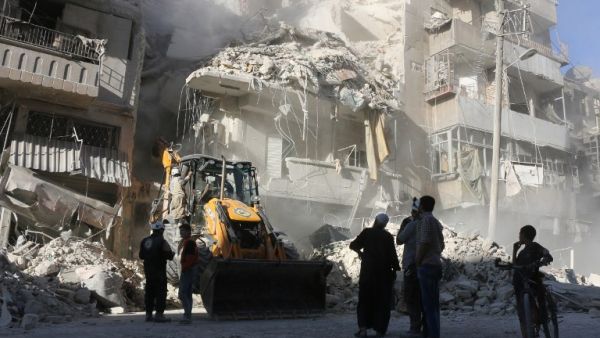 Civilians watch as a tractor clears the rubble following Syrian government forces airstrikes in the rebel held neighborhood of Tariq a-Bab in Aleppo on September 24, 2016. (AFP/Thaer Mohammed)