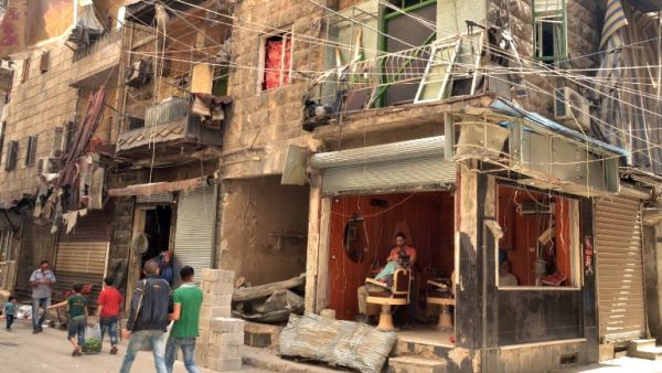 People walk past a damaged barbershop in a government-controlled district of the northern Syrian city of Aleppo on May 21, 2016. (AFP/George Ourfalian)
