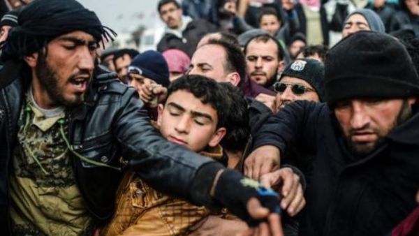 Syrian refugees jostle each other near the Turkish border crossing on February 6, 2016. (AFP/File)