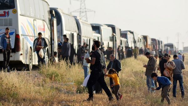 Syrian people walk near buses as a convoy carrying opposition fighters and their families from rebel held areas south of Damascus arrived near al-Bab. (Rami al SAYED / AFP)
