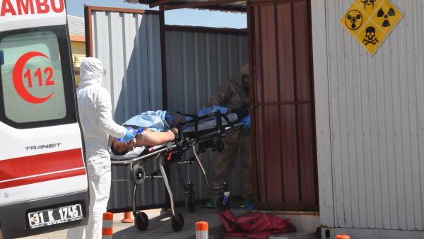 An injured Syrian is taken from an ambulance in Hatay province by Turkish officials wearing protective clothing, 4 April 2017. (AFP/Dogan News Agency)