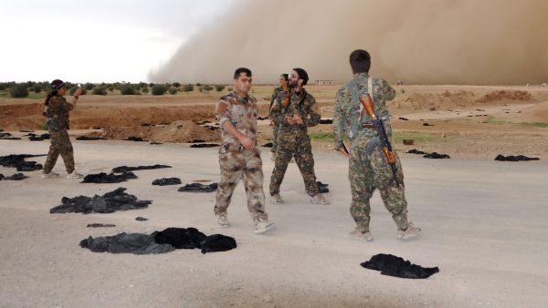 Fighters from the Syrian Democratic Forces stand amongst black abyays discarded by women escaping Daesh territory. (AFP/Ayham al-Mohammad)
