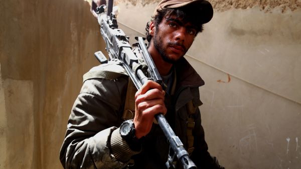 A fighter from the Syrian Democratic Forces poses with a machine gun in Tabqa, April 30 2017. (AFP/Delil Souleiman)