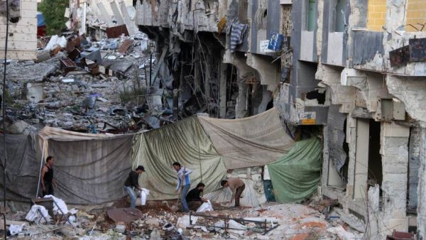 Rebel fighters dig and fill sandbags for barricades behind a sniper curtain to protect them from government forces in the southern Syrian city of Daraa. (AFP)