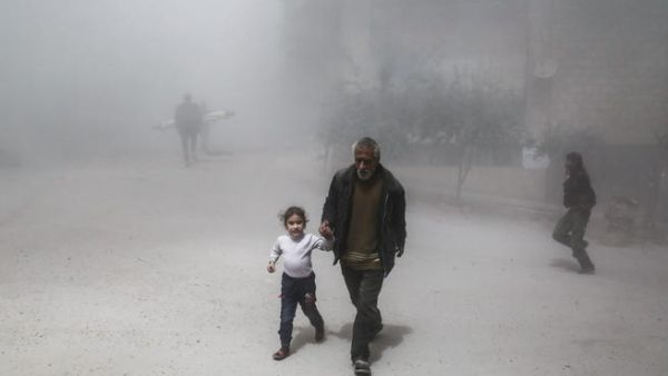 A Syrian man and girl flee following a reported government air strike on the rebel-controlled town of Hamouria. (AFP/ File Photo)