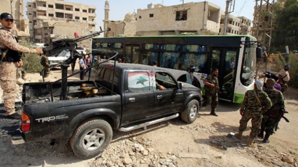 Syrian government troops stand guard as rebel fighters and their families are evacuated by bus from Daraya outside Damascus, under a plan to end a brutal four-year siege (AFP/Youssef Karwashan)