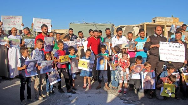 Syrians gather on July 12, 2017 with pictures of victims of a suspected toxic gas attack (Omar haj kadour/AFP)