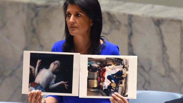 US Ambassador to the UN, Nikki Haley holds photos of victims as she speaks as the UN Security Council meets in an emergency session at the UN on April 5, 2017, about the suspected deadly chemical attack that killed civilians, including children, in Syria. (AFP/Timothy A. Clary)