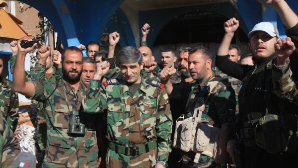 Members of the Syrian Army celebrate reclaiming the Kweires airbase earlier this week, shortly before recapturing Al-Hader, also in Aleppo. (AFP/George Ourfalian)