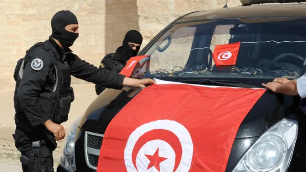 Tunisian Police Special Unit agents fix a national flag on their vehicle in front of the Okba Ibn Nafaa mosque in the central Tunisian city of Kairouan. (Fethi Belaid/ AFP)