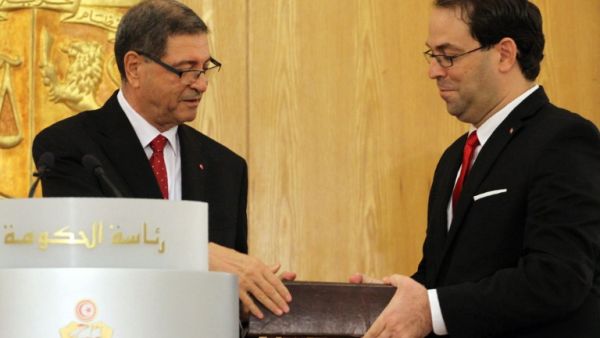 Tunisia's new Prime Minister Youssef Chahed and outgoing PM Habib Essid exchange documents during the handing-over ceremony in Carthage on August 29, 2016. (AFP/Stringer)