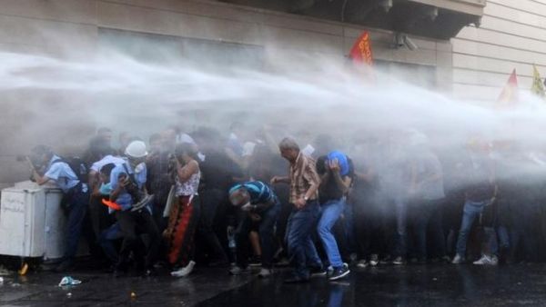Protesters take cover from a water cannon during clashes with police on Istiklal Avenue in Istanbul on July 6 (AFP)
