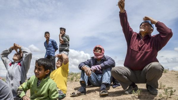 People look on as warplanes carry out bombing nearby in Kilis on May 7, 2016. (AFP/Ilyas Akengin)