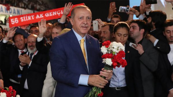 Turkish President Tayyip Erdogan gives flowers to his supporters upon his arrival at the Extraordinary Congress of the ruling AKP (AFP)