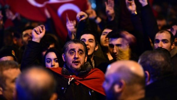 People gesture and wave flags as Turkish residents of the Netherlands gather for a protest outside Turkey's consulate in Rotterdam on March 11, 2017. [AFP/Emmanuel Dunand]