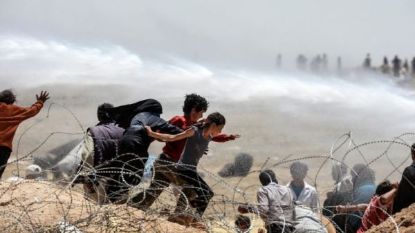 Syrian refugees run away as Turkish soldiers use water cannon to move them away from fences along the Turkish border. [AFP/Bulent Kilic]