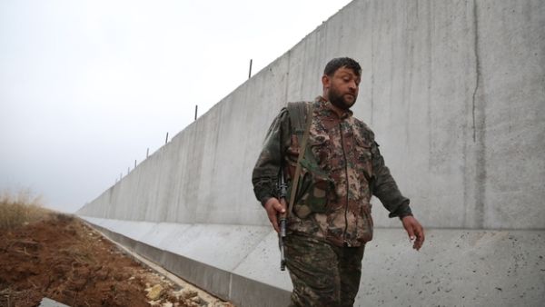 A YPG fighter walks along the Turkish-Syria border wall. (AFP/File)