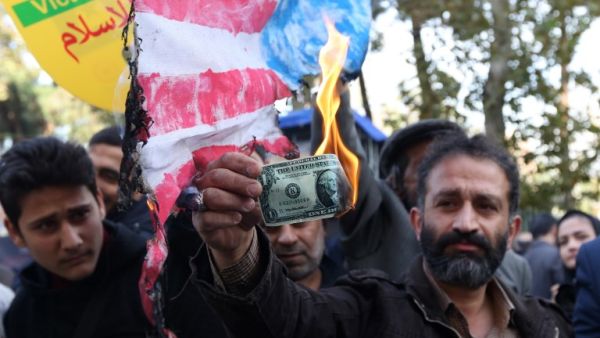 An Iranian protester burns a dollar banknote during a demonstration outside the former US embassy in the Iranian capital Tehran on November 4, 2018. (ATTA KENARE / AFP)