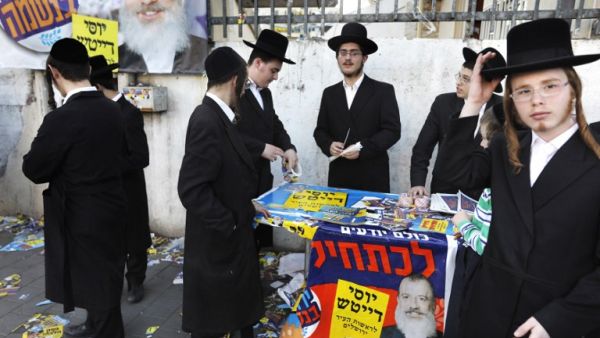 Ultra-Orthodox Jewish men stand next to campaign posters of municipal candidate Yossi Daitch outside a polling station, in Jerusalem on October 30, 2018. (MENAHEM KAHANA / AFP)