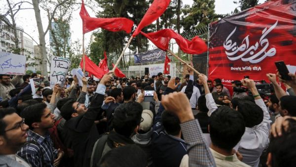 Iranians chant slogans and wave red flags defaced with the "Down with USA" slogan during an anti-US protest outside the former US embassy headquarters in Tehran, May 9, 2018. Iranians reacted with sadness, resignation and defiance  to U.S. President Donald Trump's withdrawal from the nuclear deal. ATTA KENARE/AFP