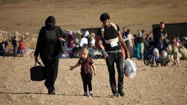 Syrians walk carrying their belongings after crossing the Syria-Jordan border. (AFP)
