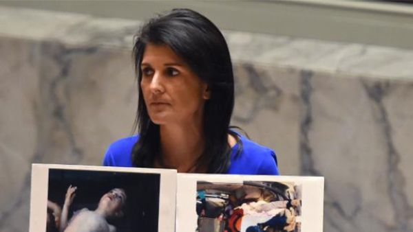 US Ambassador to the UN, Nikki Haley holds photos of victims as she speaks as the UN Security Council. (AFP)
