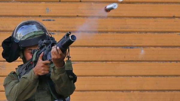 An Israeli soldier fires a tear gas canister during clashes with Palestinian protesters in the center of the occupied West Bank city of Hebron on July 13, 2018. (AFP photo)