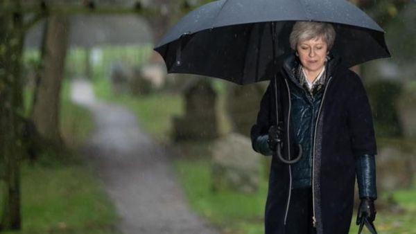 Britain's Prime Minister Theresa May shelters from the rain under an umbrella. (AFP/ File Photo)