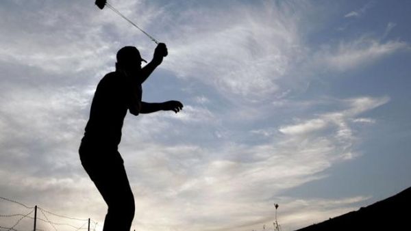 متظاهر فلسطيني يرمي جنود الاحتلال بالحجارة خلال مواجهات في نابلس بالضفة الغربية تضامنا مع غزة/أ.ف.ب