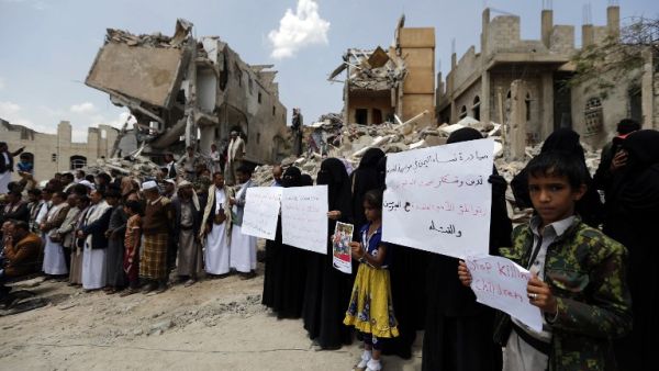 Yemenis stand in protest amidst the debris of a house, hit in an air strike on a residential district, in the capital Sanaa on August 26, 2017 (AFP)