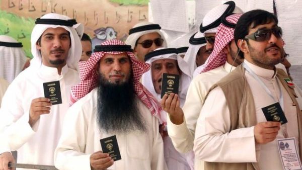 KUWAIT, KUWAIT CITY : Kuwaiti men display their identity cards as they wait to cast their votes at a polling station in Kuwait City on July 27, 2013. AFP PHOTO/YASSER AL-ZAYYAT