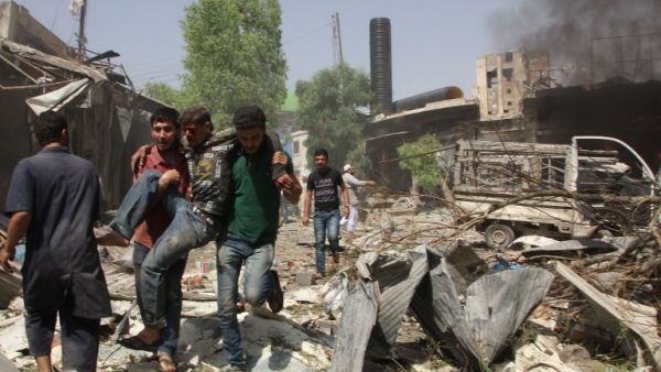 Syrian men help an injured person after a reported barrel bomb attack by Syrian government forces hit an open market in the northern city of Aleppo, on June 3, 2015, killing and injuring people. (AFP/Karam al-Masri)