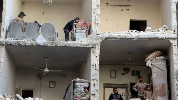 Civilians examine the bombed-out remains of a house in Aleppo, Syria following airstrikes in December 2015.  (AFP/Karam al-Masri)