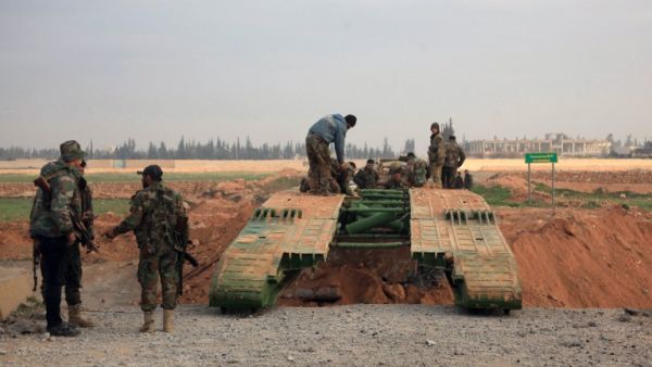 Members of the government forces install a retractable military bridge to cross a trench on the eastern outskirts of the Syria's northern embattled city of Aleppo after they re-took the area from Daesh fighters on February 21, 2016. (AFP/George Ourfalian)