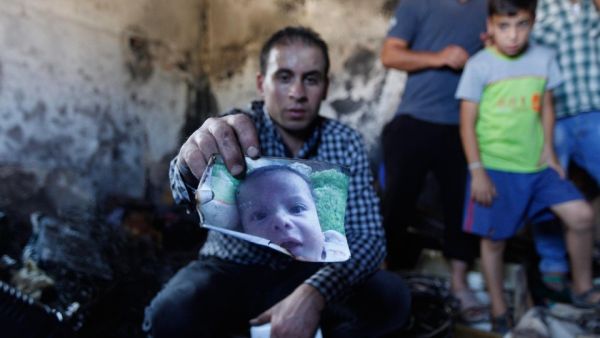A family member holds up a photo of Ali Dawabsheh, a Palestinian toddler killed last week by Israeli settlers in an arson attack on his home.  (AFP/Majdi Mohammed)