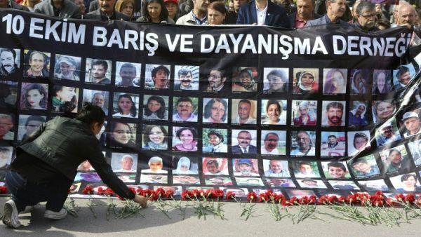 A wonam lays red carnations as people hold a banner with pictures of victims of October 10 bombings during a memorial ceremony in Ankara on April 10, 2016. (AFP/Adem Altan) A wonam lays red carnations as people hold a banner with pictures of victims of October 10 bombings during a memorial ceremony in Ankara on April 10, 2016. (AFP/Adem Altan)