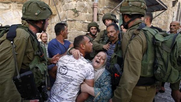 A Palestinian woman tries to prevent the arrest of a Palestinian man by Israeli soldiers in the southern occupied West Bank city of al-Khalil (Hebron) on September 20, 2016. (AFP)