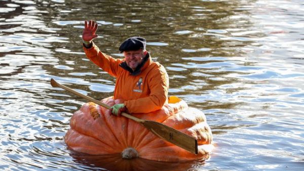 A triumphant Tom Pearcy waves from his pumpkin boat. (Screenshot)