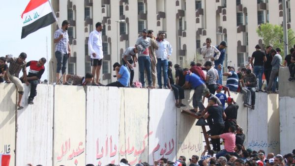 Iraqi protesters climb over a concrete wall surrounding the parliament (unseen) after breaking into Baghdad's heavily fortified "Green Zone" on April 30, 2016. (AFP/Haidar Mohammed Ali)
