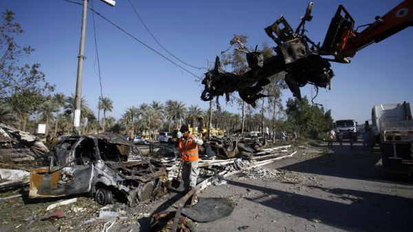 Iraqi emergency responders clear debris from the site of a truck bomb, that exploded at a crowded checkpoint, in the Iraqi city of Hilla, south of Baghdad on March 6, 2016. (AFP/Haidar Hamdani)
