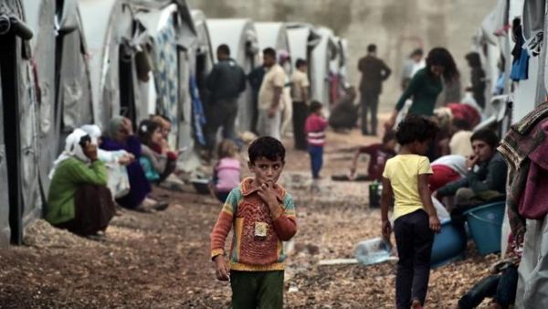 A boy walks past tents in a Syrian Kurdish refugee camp in the Turkish town of Suruc (AFP/Aris Messinis)