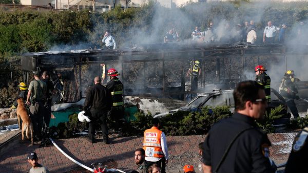 Israeli security forces respond to the burning remains of the bus bombed by a Hamas operative in April. (AFP/File)